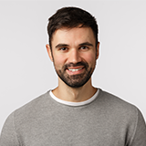 A man with a beard and mustache wearing a gray shirt.