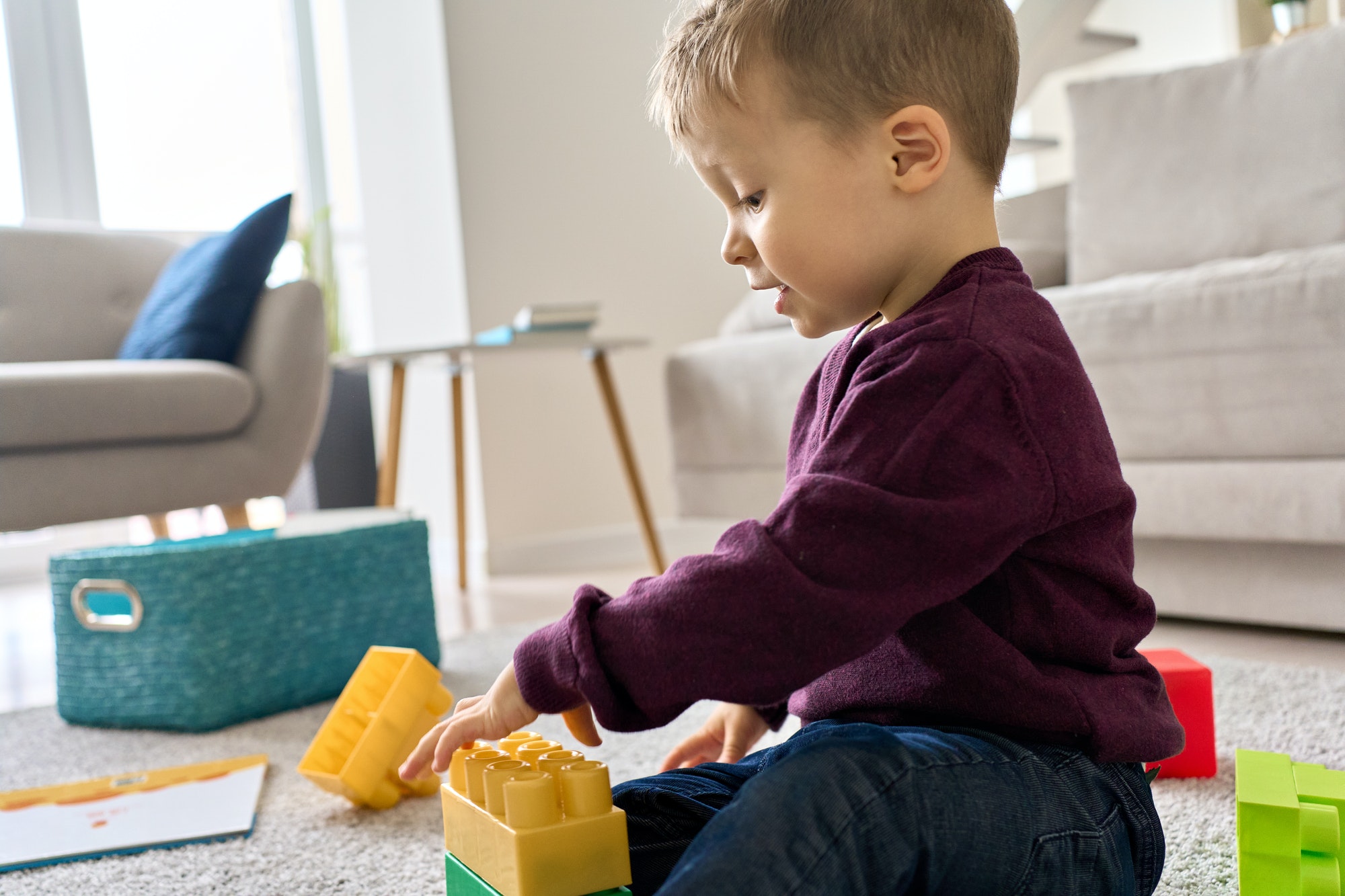 Cute preschool toddler kid boy playing sitting on floor at home.